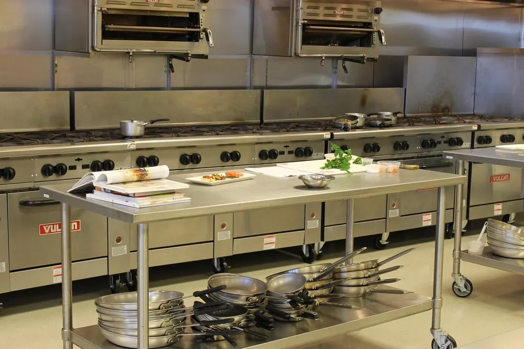 Commercial kitchen with stainless steel ranges and prep tables